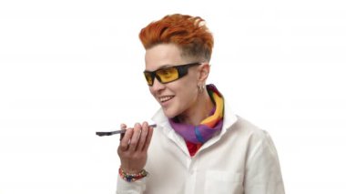 Canlı kızıl saçlı ve son moda güneş gözlüklü mutlu bir lezbiyen hoparlörde coşkuyla konuşuyor, özgürlük ve neşe hissi yayıyor. Kamera 8K HAM. 