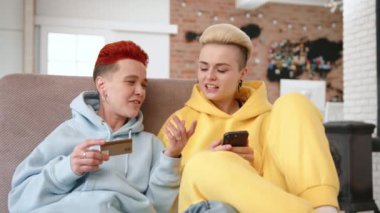 LGBT topluluğunun bir parçası olan iki kadın, ortaklıkları içindeki mali güveni sembolize ederek telefonlarında güvenli bir çevrimiçi işleme giriyorlar. Yüksek kalite 4k görüntü