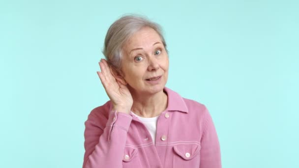 这段视频拍摄了一位穿着粉色夹克的好奇的老妇人 她的手按在耳朵上 摆出典型的偷听姿势 她专注的表情暗示她正在敏锐地聆听对话 — 图库视频影像