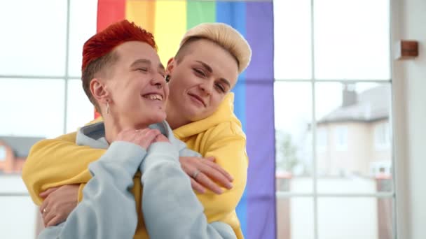 Ambiente Doméstico Duas Lésbicas Capuzes Azuis Amarelos Vibrantes Abraçam Alegremente — Vídeo de Stock