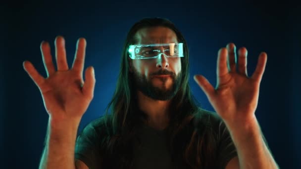 Zaostřený Muž Holografických Brýlích Stojí Před Tmavomodrým Pozadím Ruce Sepjaté — Stock video