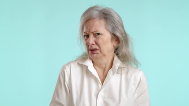嫌な表情をした高齢の女性は 軽い青色の背景と隔離された嫌悪感 反発または失望感で顔を走らせます カメラ Raw — ストック動画
