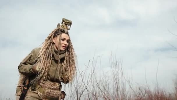 一名身穿全套伪装装备的女狙击手小心翼翼地穿过一片冬季的森林 为行动寻找一个战略地位 8K照相机 — 图库视频影像