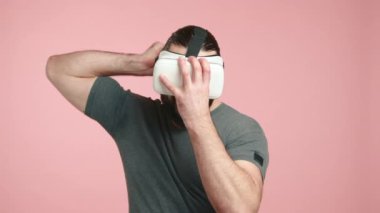 Bir adam, VR kulaklığını takarken, heyecan verici bir sanal gerçeklik deneyiminin içine dalmaya hazırlanırken görüntülenir. Kamera 8K HAM. 