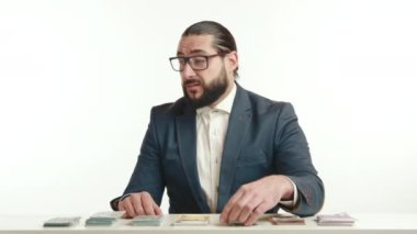 Beklenmedik bir saygısızlıkla, mavi ceketli ve beyaz gömlekli bir iş adamı masasında 100 dolarlık bir banknotu yırtarak bir anlık mali karar ya da protestoyu somutlaştırıyor. Kamera 8K HAM. 
