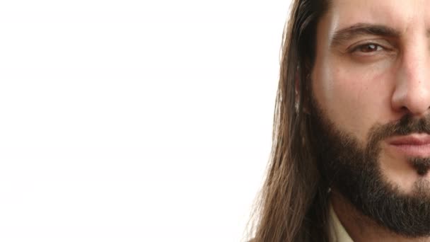 一个有着黑色胡子和长发的严肃男子的半张脸的特写 在白色的背景上表现出一种紧张而深沉的表情 8K照相机 — 图库视频影像