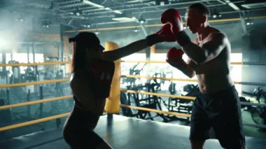 Genç bir bayan boksör boks ringinde antrenman yapıyor, dövüş performansını arttırmak için yumruk becerilerini ve tekniğini geliştiriyor. Kamera 8K HAM. 