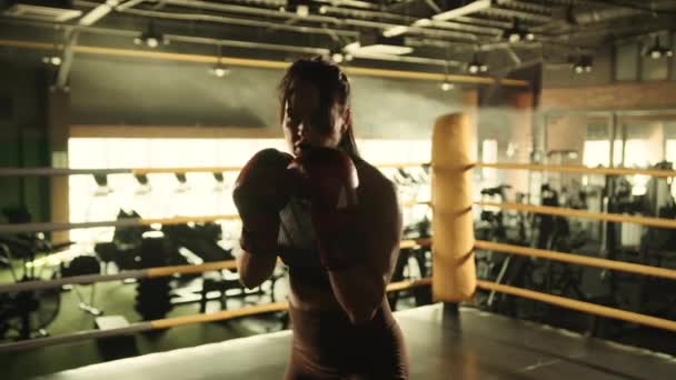 一位女拳击手在对着摄像机直拳时 以一种展示她强大战斗技巧的精神在体育馆里训练 从而引导出她的激情和精准 — 图库视频影像
