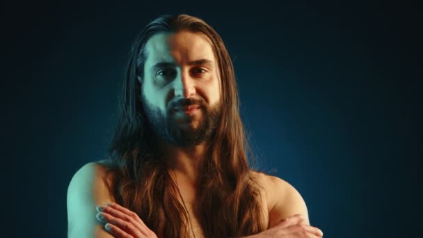 这个留着长胡子和长发的赤裸胸部男人 站在黑暗的背景下 以反思的姿态 用直视的目光散发出自信和沉着 8K照相机 — 图库视频影像