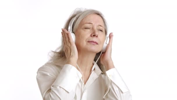 放宽心的老妇人平静地闭上眼睛 通过耳机听着宁静的音乐 传达着一种平静和满足的心情 8K照相机 — 图库视频影像