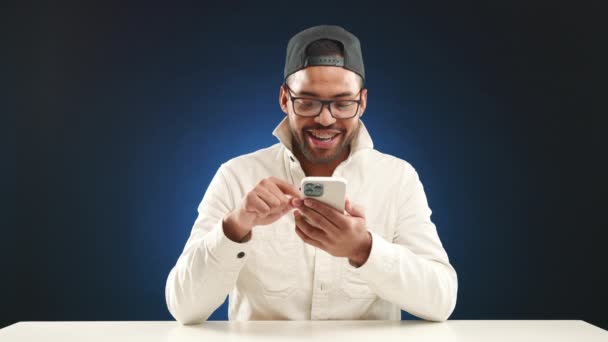 Homem Sorridente Com Óculos Boné Deliciosamente Envolvido Com Seu Smartphone — Vídeo de Stock