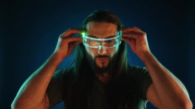 Yenilikçi bir adam, çevresindeki mavi ışıkla çevrili projeksiyonlu bir klavyeye yazmadan önce sanal gerçeklik gözlüklerini ayarlar. Kamera 8K HAM. 