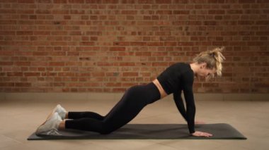 Bir fitness düşkünü çağdaş bir spor salonunda diz kapağı vuruşlarını gösterir, çekirdek dengesi ve üst vücut koordinasyonuna odaklanır, forma uygun egzersiz kıyafetleri giyer. Kamera 8K HAM.