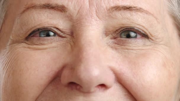 特写镜头抓住了一个微笑的老妇人闪烁的眼睛 她的皱纹证明了她的生活充实 在模糊的背景下散发出欢乐和体验 8K照相机 — 图库视频影像