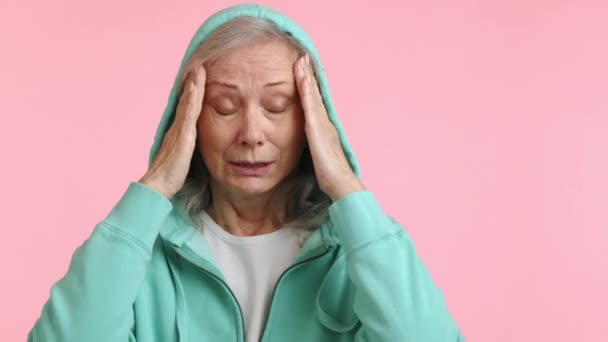 Grimaces에 그녀의 사원을 평범한 분홍색 배경에 두통이나 편두통의 증상을 보여줍니다 — 비디오
