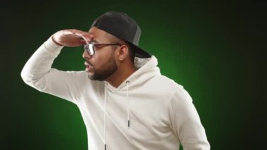 Şapkalı ve gözlüklü bir adam dikkatle durur, elini alnına koyar ufku tarar, dikkatle birini ya da bir şeyi arar. Kamera 8K HAM. 