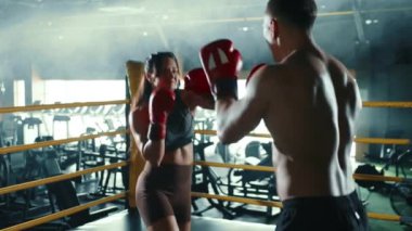 Odaklanmış bir kadın boksör ve antrenörü sıkı bir boks antrenmanına girişiyor. Spor salonunun özel bir boks ringinde teknikler ve yumruklaşıyorlar. Kamera 8K HAM.