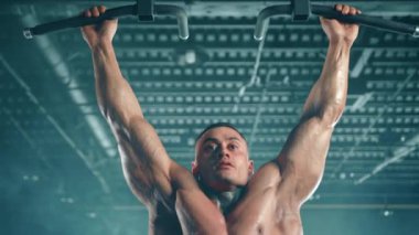 Kaslı sporcu, son model fitness ekipmanlarıyla çevrili çağdaş bir spor salonunda barfiks çekiyor. Kamera 8K HAM. 