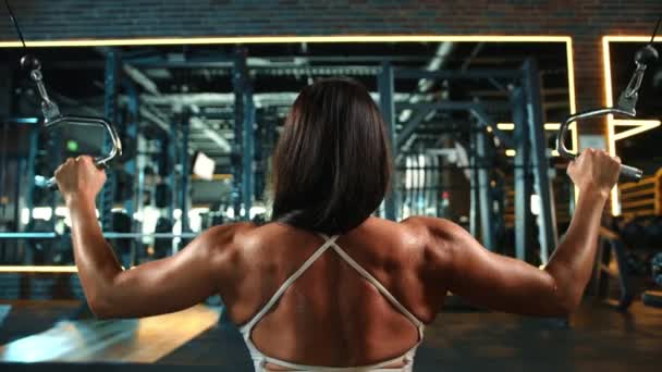 クローズアップでは 女性アスリートがクロスオーバーマシンで激しいトレーニングを行い 筋肉の健康とフィットネスへの彼女の献身の証です カメラ — ストック動画