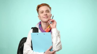 Canlı bir lezbiyen öğrenci kitap ve sırt çantasıyla ayakta duruyor, öğrenme ve kampüste yeni deneyimler için olumlu ve hazır olduğunu söylüyor.. 