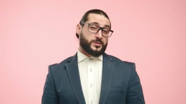 Mavi takım elbiseli ve beyaz gömlekli kafası karışmış bir adam kafa karışıklığı ve tatminsizliği ifade eder. Yüzündeki ifade, pembe arka plandaki anlayış eksikliğini ya da hoşnutsuzluğu yansıtır. Kamera 8K HAM.