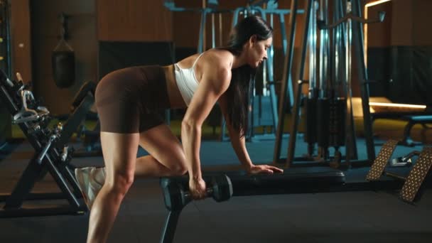 女性アスリートは 筋肉強度と安定性を向上させるために設計されたダンベル列を実行することに焦点を当てています カメラ Raw — ストック動画