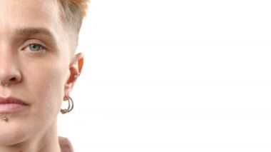 Sanatsal açıdan yakın plan bir fotoğraf genç bir kadının ince detaylarını, yarım yüzünü, piercinglerine vurgu yaparak, titiz beyaz bir arkaplana karşı çekiyor.. 