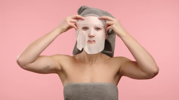 Młoda Biała Kobieta Szarym Ręczniku Nakładająca Twarz Maskę Prześcieradło Nawilżające — Wideo stockowe