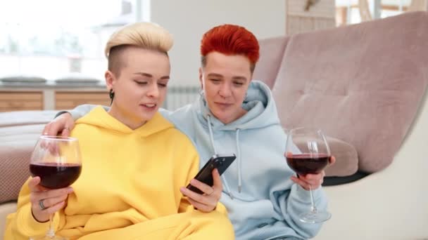 在舒适的家庭环境中 一对同性恋夫妇一边欣赏红酒 一边在智能手机屏幕上分享欢笑 营造出欢乐与家庭和谐的氛围 8K照相机 — 图库视频影像