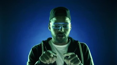 Fütüristik holografik gözlüklü bir adam sanal bir klavyeye yoğun bir şekilde daktilo kullanıyor, tamamen artırılmış bir gerçeklik ortamına dalmış. Kamera 8K HAM. 