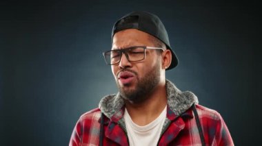 Diş teli takan Afro-Amerikalı bir adam, muhtemelen sevimsiz bir kokuya tepki göstererek, gözlük takarak yüzünü buruşturuyor. Kamera 8K HAM. 