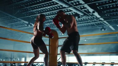 Bir boks salonunda, bir erkek ve kadın boksör dinamik bir antrenman sırasında teknik ve ortaklık gösterirken yakalanır. Kamera 8K HAM. 