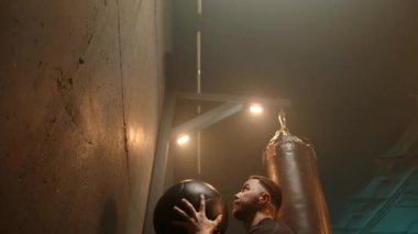 Kararlı bir adam sağlık topu kullanırken spor salonunda güç ve dayanıklılık gösterir. Fitness, vücut geliştirme ve egzersiz temaları için idealdir. Ekran, fiziksel refaha olan bağlılığı yansıtır.