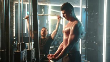 Spor salonunda, iki erkek sağlık ve refahı temsil eden çeşitli ekipmanlarla güçlü bir şekilde antrenman yaparak spor yapmaya kendini adamıştır.