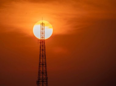 Sihouette of telecommunication pole or satellite radio station tower with big sun background