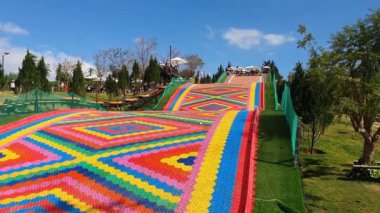 Da Lat, Viet Nam- 25 Şubat 2024: Heyecanlı bir oyun adı taşıyan genç turist grubu yüzüyor, gökkuşağı klorlu halıda yüzüyorlar hızla aşağı dalıyorlar, heyecan verici bir şekilde Mongo bölgesi, Dalat, Vietnam 'da birlikte eğleniyorlar