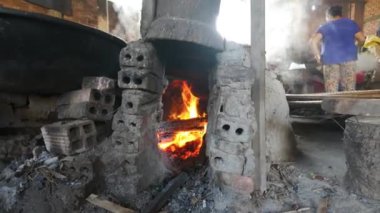 Vietnamlı kadın pirinç unundan pirinç kağıdı ya da banh trang yapıyor, dumanlı kömür ocağı el yapımı kek için yükseliyor, Ben Tre, Vietnam