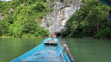 QuANG BINH, VIET ismi - 14 Haziran 2024: Tekne dar bir mağara kapısından Phong Nha Ke Bang Ulusal Parkı 'na gider, kireçtaşı dağının çekim formasyonu, yer altı varış noktası,