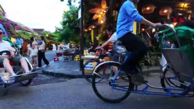 HOI AN, VIET NAM - 18 HAZİRAN 2024: Hoian antik kentinde kalabalık insanlar alacakaranlıkta, turist seyehat şehirleri bisiklet veya çocuk arabaları, yaz tatilinde renkli ışık manzarası, harika bir klasik miras