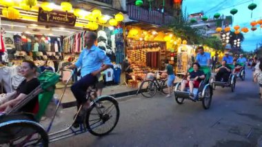 HOI AN, VIET NAM - 18 HAZİRAN 2024: Hoian antik kentinde kalabalık insanlar alacakaranlıkta, turist seyehat şehirleri bisiklet veya çocuk arabaları, yaz tatilinde renkli ışık manzarası, harika bir klasik miras
