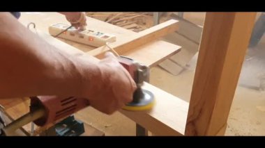 Aile projesi için çalışan bir adam, elinde zımpara makinesiyle, erkek ahşap kaplama yüzeyi iç mobilyaları bitirmek için, talaş ev tozu yapar.