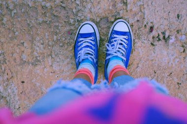 Beyaz bağcıklı klasik mavi spor ayakkabılar, dinlenme yeri beton, renkli çoraplı ayakkabılar. Şehir tarzında kaygısız gençliğin beklediği ya da düşündüğü bir an.