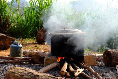 Tet bayramı için geleneksel Vietnamlı aşçı Banh Tet 'in kültür mutfağı olması gibi doğa tarafından çevrelenmiş tuğla ve taştan yapılmış geçici bir ocağın üzerinde açık ateşte buharlaşan siyah bir tencere.