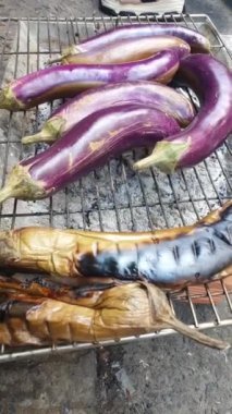 Kömürde kızartılmış patlıcan, açık pazarda günlük yiyecekler, yeşil soğanlı sokak yemekleri yemeye hazır.