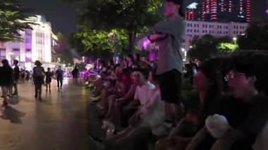HO CHI MINH CITY, VIET NAM - 26 AUG 2024: Nguyen Hue caddesinde gece vakti hareketli atmosfer, kalabalık gençlik ve arkadaşları kamusal alanlarda toplanıyor, hafta sonu gecesi çok eğlenceli