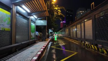 HO CHI MINH CITY, VİETNAM - SEPT 18.2024: Geceleri Ben Thanh otobüs durağı, bükümde oturan insanlar seyahat için kamu araçlarını, yağmurda renkli aydınlık caddeleri bekliyorlar