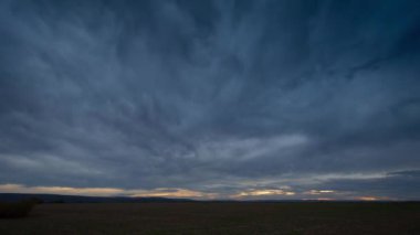 Gün batımında bulutlar güneş ışınlarıyla ovaların üzerinde uçar.