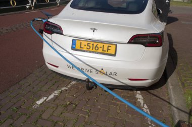 Maastricht, Hollanda - 12 Ekim 2022: Bataryayı şarj etmek için beyaz elektrikli Tesla aracı