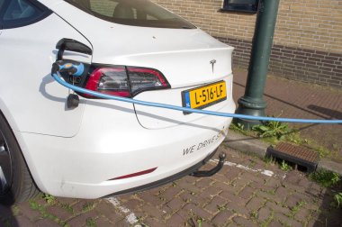 Maastricht, Hollanda - 12 Ekim 2022: Bataryayı şarj etmek için beyaz elektrikli Tesla aracı