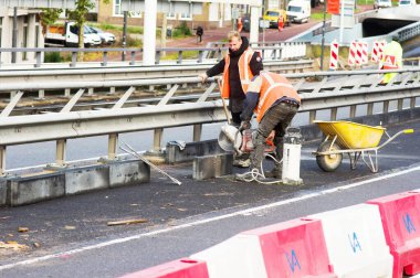 Arnhem, Hollanda - 4 Kasım 2022: Turuncu güvenlik yeleği giyen iki kişi tarafından sokakta inşaat faaliyetleri